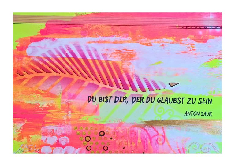 Bunte Wandmalerei mit dem deutschen Zitat 'Du bist der, der du glaubst zu sein' von Anton Saur, umgeben von abstrakten, farbenfrohen Formen und Mustern in Orange, Pink, Grün und Blau.